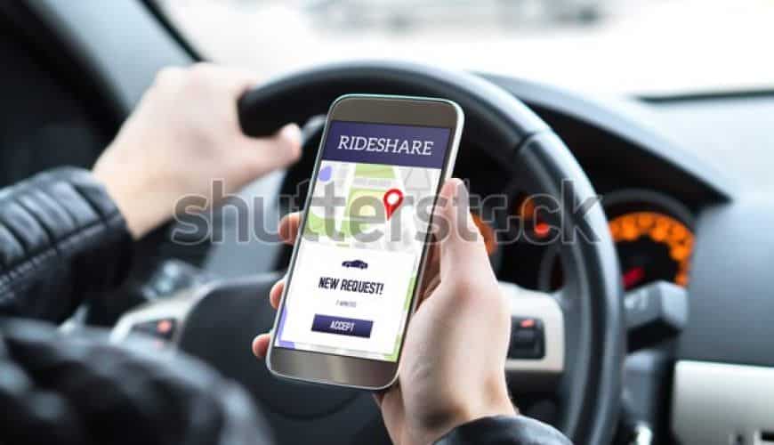Personne conduisant avec une application de covoiturage ouverte sur le smartphone.
