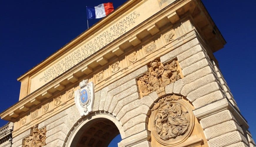 Arc en pierre décoré avec drapeau français, ciel bleu clair en arrière-plan.