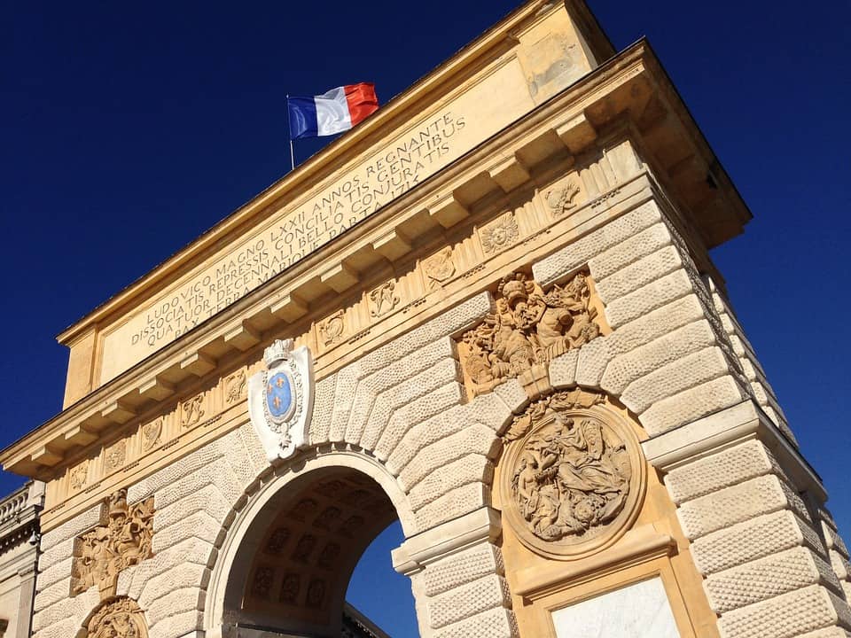 Arc en pierre décoré avec drapeau français, ciel bleu clair en arrière-plan.