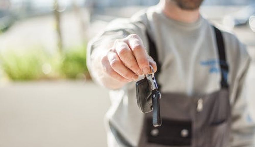 Personne tendant un trousseau de clés avec clé de voiture, arrière-plan flou.