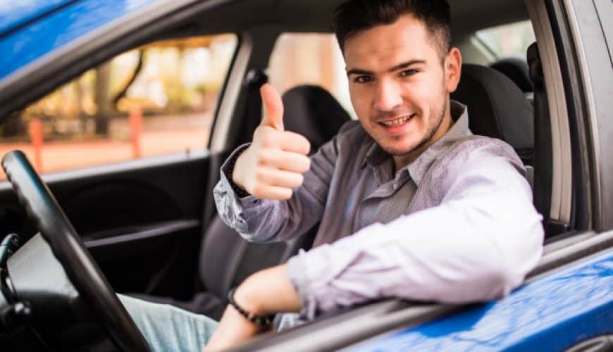 Un homme au volant d'une voiture bleue fait un geste de pouce levé.