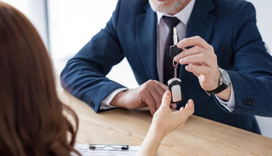 Personne en costume remettant les clés d'une voiture dans un cadre professionnel.